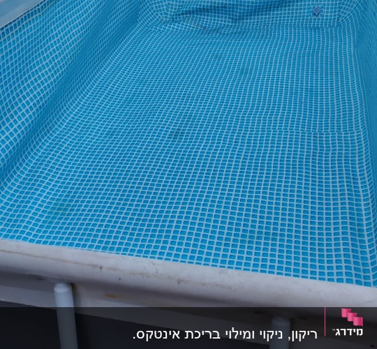 בריכת שחייה ריקה עם רשת כחולה לתחזוקה
